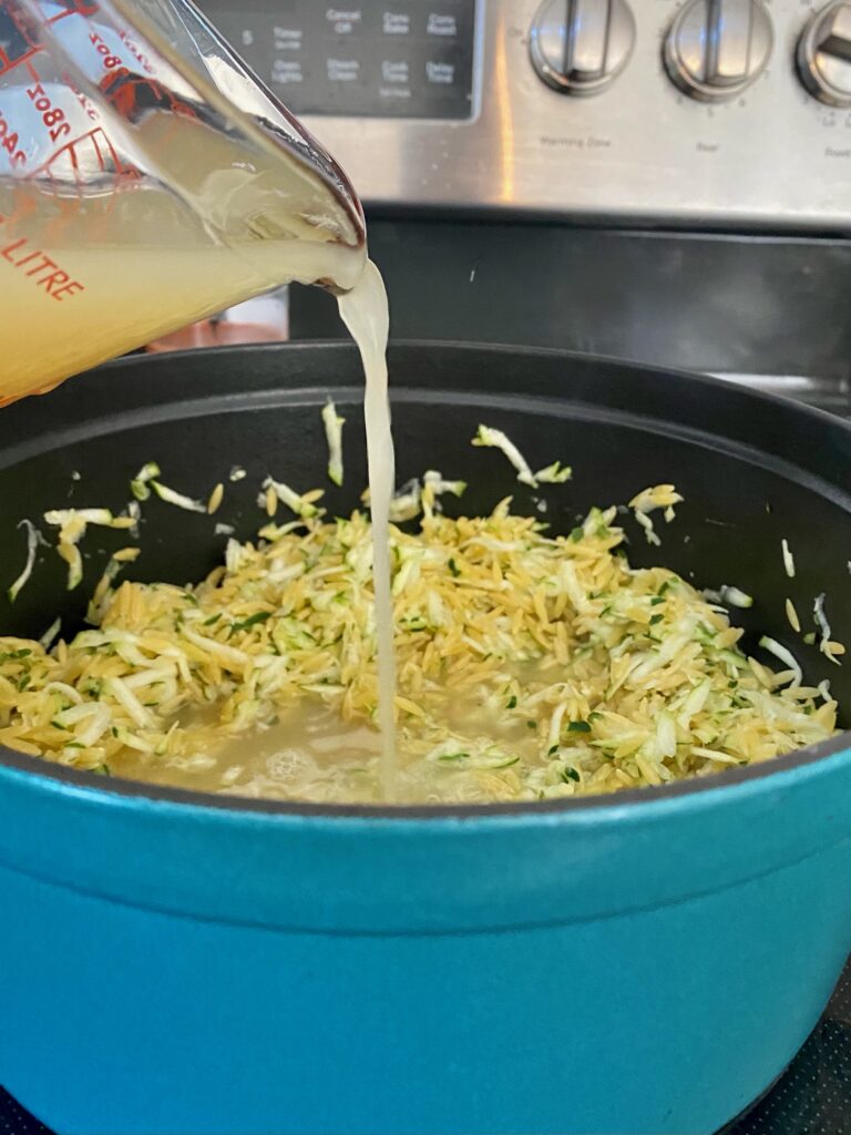 mixing zucchini and parmesan orzo 