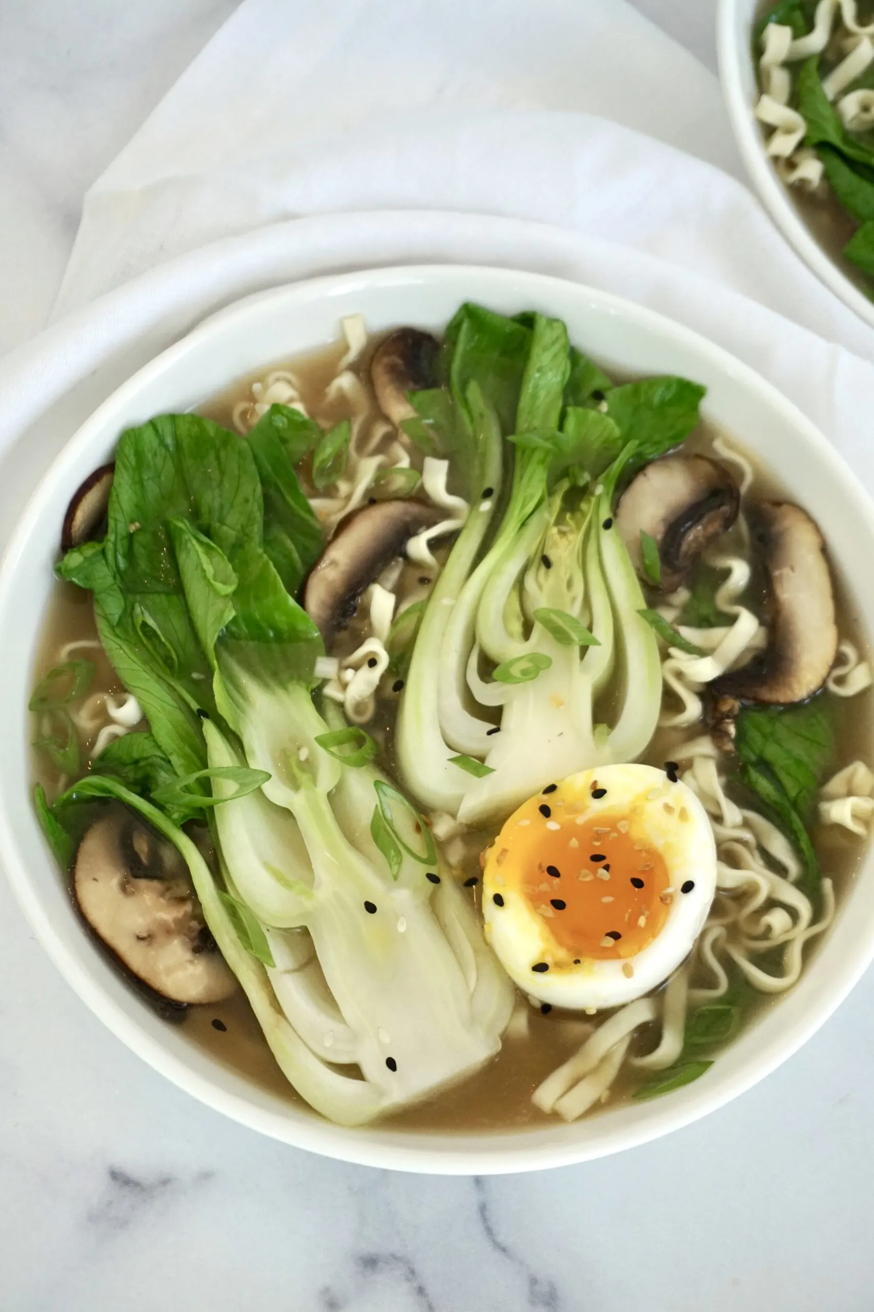 bowl of bok choy soup with noodles, bok choy, mushrooms and soft boiled egg