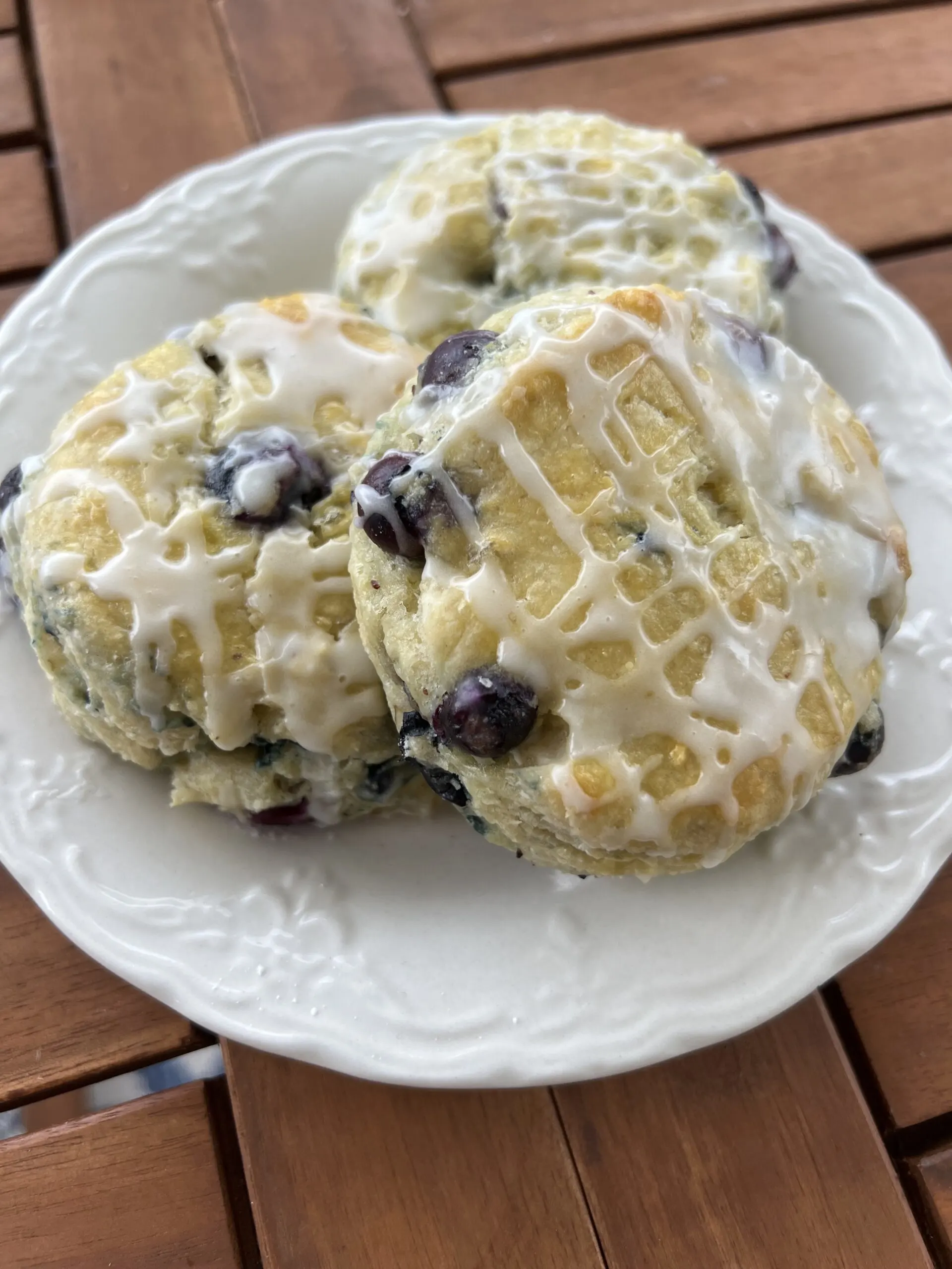 3 glazed blueberry biscuits on a small white plate